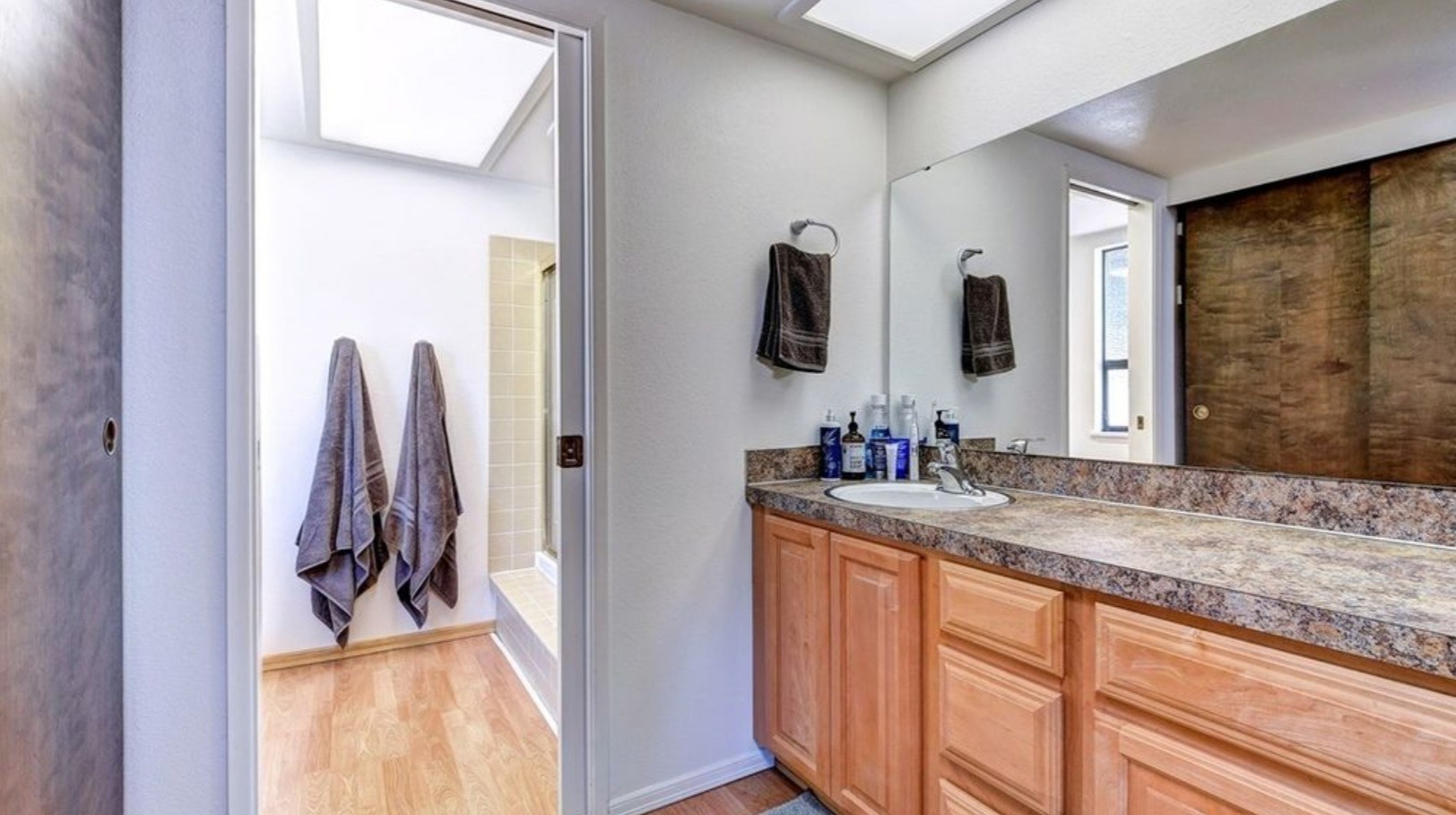 Kirkland primary bathroom before the remodel, with a single-sink vanity, sliding closet doors, and a separate tub and shower room